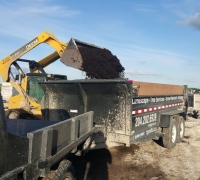 skid steer loading a dump trailer with soil